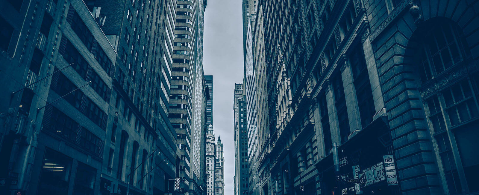 Tall city buildings creating a narrow urban canyon with a moody sky.